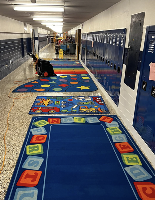 Custodial staff working in the school hallway next to lockers