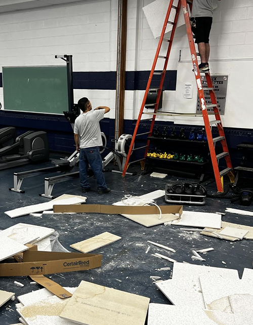 Custodial staff on a ladder in a workout room